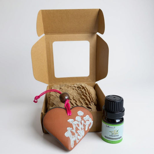Open cardboard box with heart-shaped container and bottle of essential oil on a white background