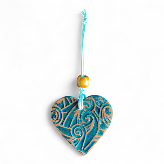 Heart-shaped dterracotta essential oil diffuser with blue and brown patterns on a white background