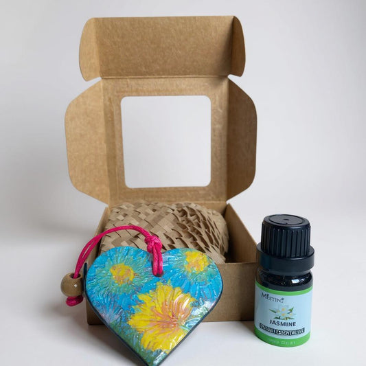 Open cardboard box with a heart-shaped decorative item and a bottle of essential oil on a white background