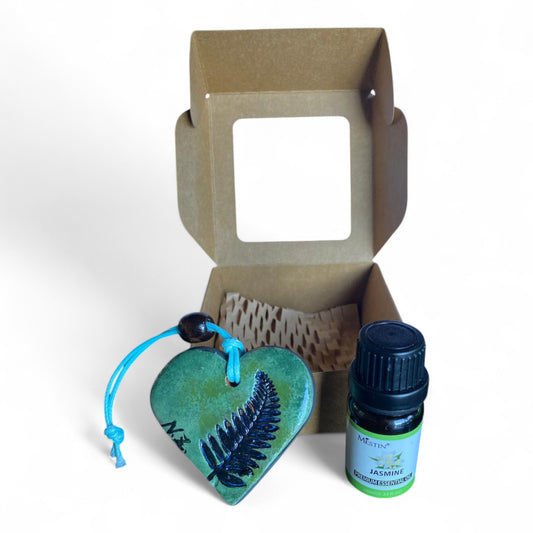 Terracot heart shaped essential oil diffuser in front of giftbox with bottle of essential oil.