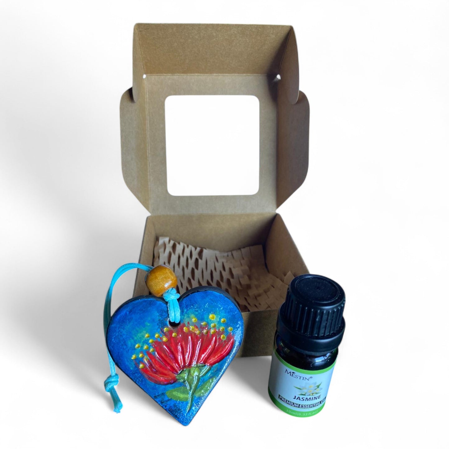 Terracot heart shaped essential oil diffuser in front of giftbox with bottle of essential oil.