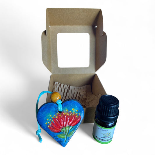 Terracot heart shaped essential oil diffuser in front of giftbox with bottle of essential oil.