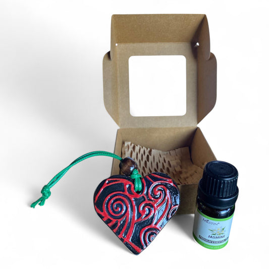 Terracot heart shaped essential oil diffuser in front of giftbox with bottle of essential oil.