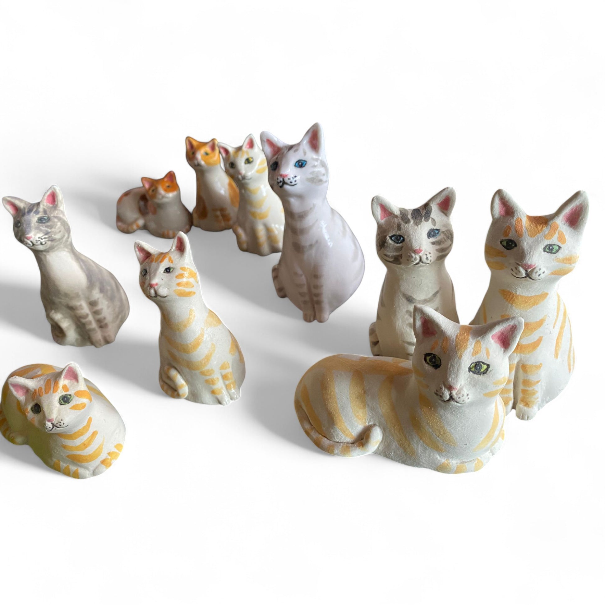 Collection of porcelain cat figurines on a white background