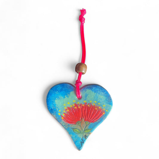 Heart-shaped ornament withNew Zealand Pohutukawa design and red string on a white background