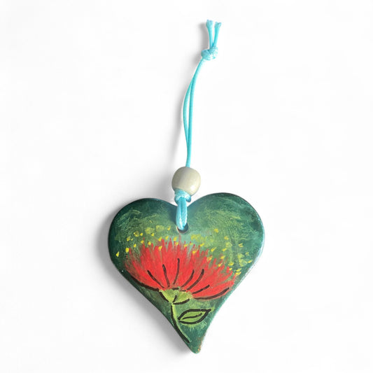 Heart-shaped ornament withNew Zealand Pohutukawa design and red string on a white background