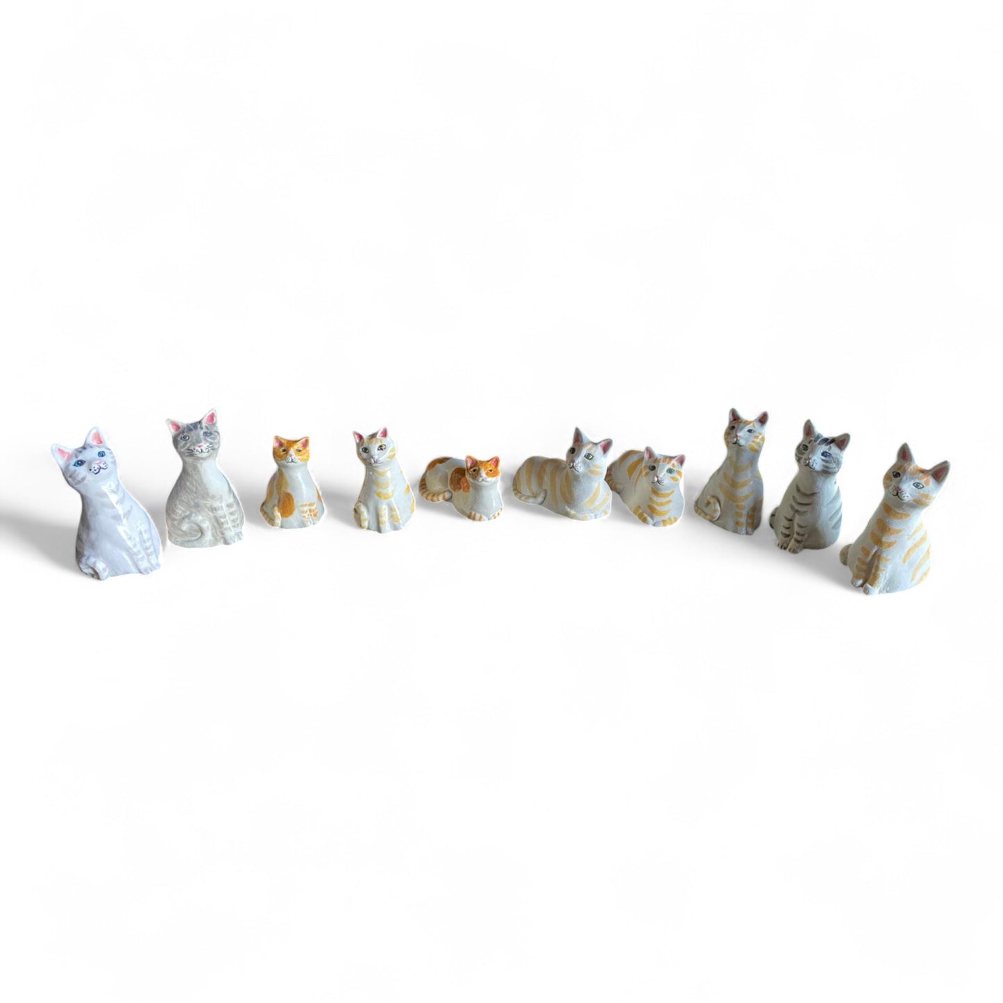 Collection of porcelain cat figurines on a white background