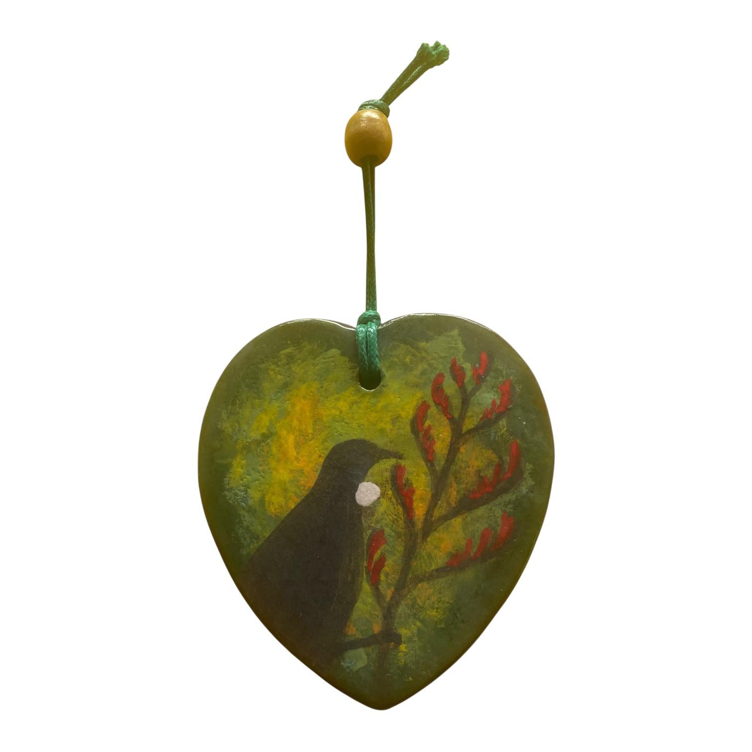 Heart-shaped ornament with a Tui bird design on a white background