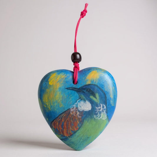 Heart-shaped ornament with a New Zealand native bird the Tui design on a pink string against a light gray background