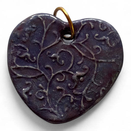 Heart-shaped pendant with intricate design on a white background