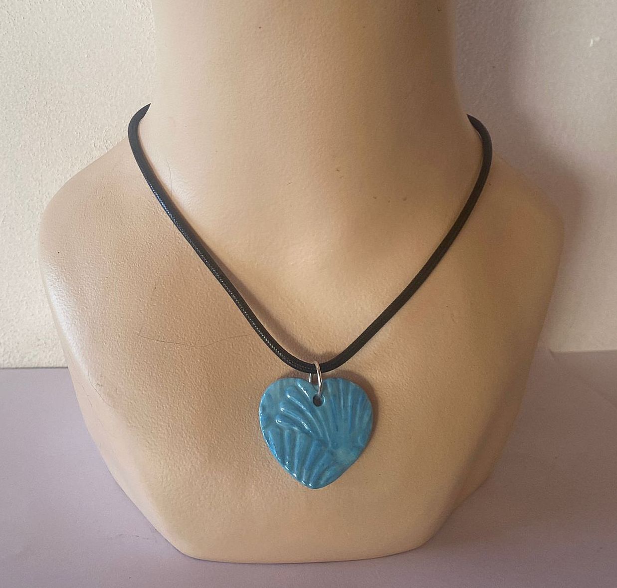 Necklace with a blue heart-shaped pendant on a mannequin bust.