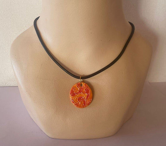 Necklace with a decorative orange pendant on a mannequin neck against a neutral background