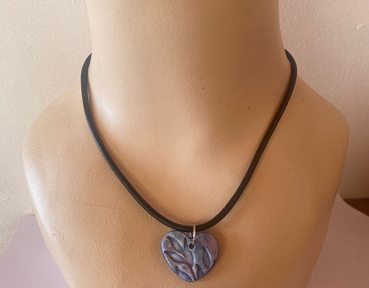 Necklace with a heart-shaped pendant on a mannequin neck against a plain background