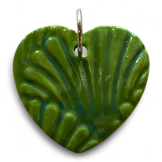 Green heart-shaped pendant with scallop shell pattern on a white background