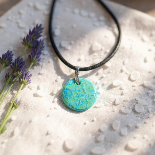 Necklace with a turquoise pendant on a textured surface with lavender flowers.