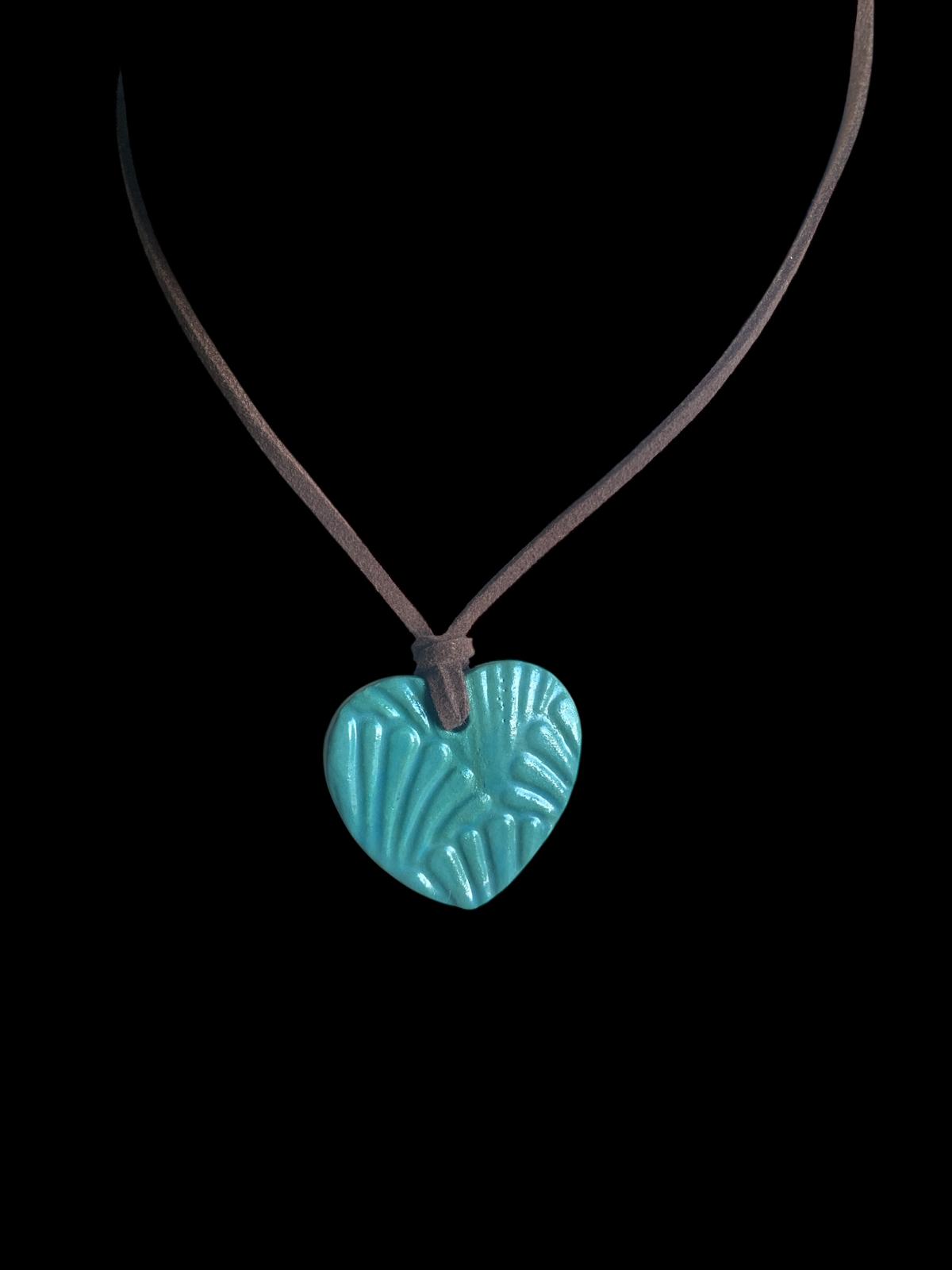 Turquoise heart-shaped pendant on a brown cord against a black background