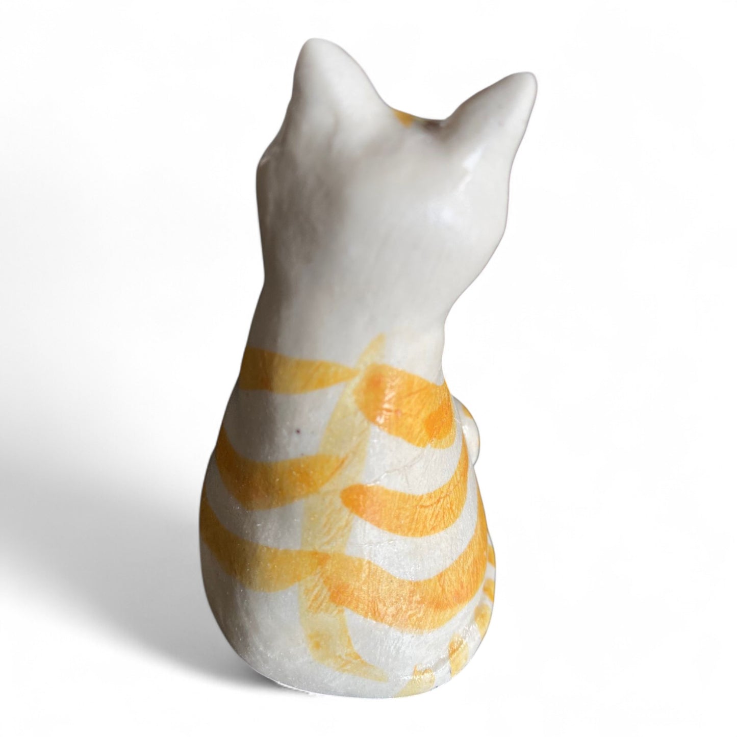 Porcelain cat figurine with orange and white stripes on a white background