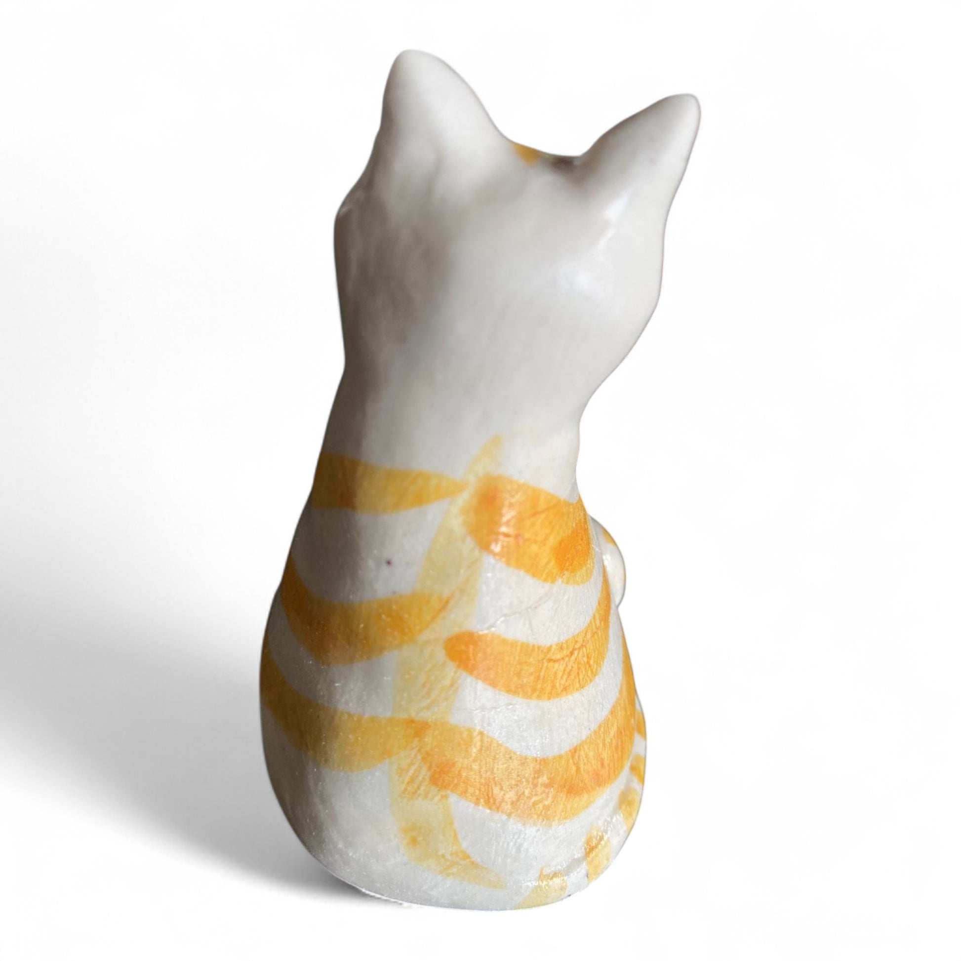 Porcelain cat figurine with orange and white stripes on a white background
