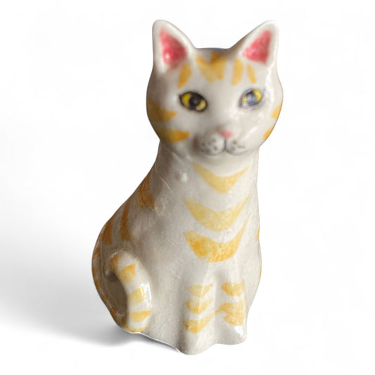 Porcelain cat figurine with orange and white stripes on a white background
