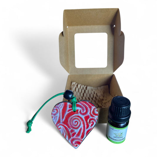 Terracot heart shaped essential oil diffuser in front of giftbox with bottle of essential oil. Maori Design