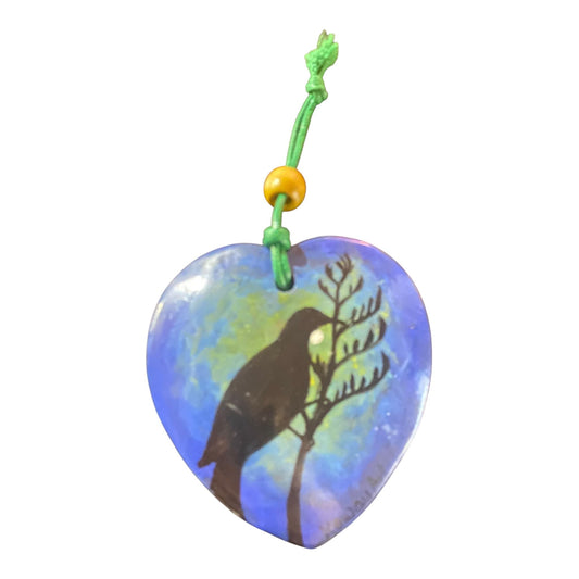 Heart-shaped pendant with Tui bird silhouette design on a white background