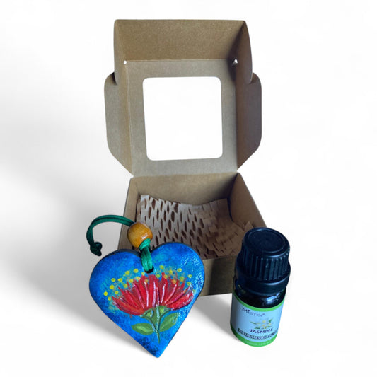 Terracot heart shaped essential oil diffuser in front of giftbox with bottle of essential oil.