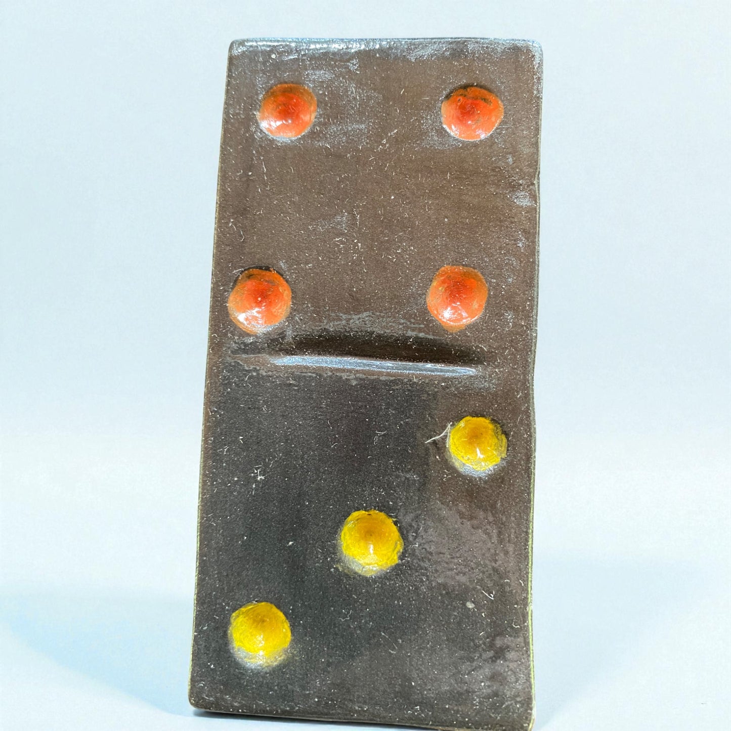 Domino with red and yellow dots on a light blue background