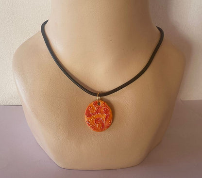 Necklace with a decorative orange pendant on a mannequin neck against a neutral background