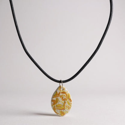 Necklace with a yellow floral pendant on a light gray background